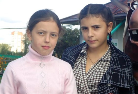 In this Sept. 11 photo, 12-year-olds Anna, left, and Irina, right, pose in the city of Kopeisk in Russia's Ural Mountains. Two Russian families on Monday won $100,000 compensation each from a maternity home that accidentally switched their daughters at birth.